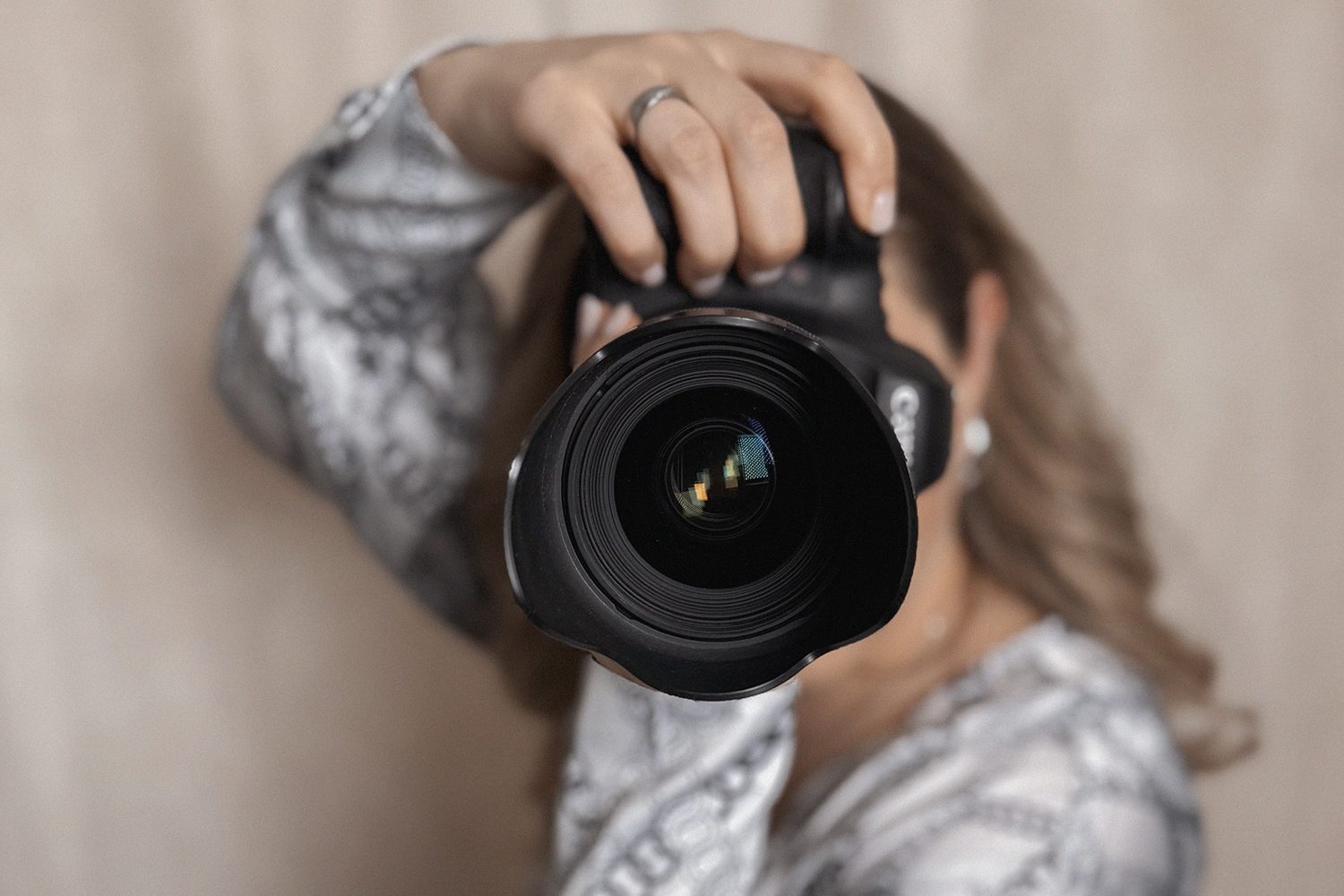 Eine Frau hält eine Kamera in der Hand und blickt durch das Objektiv.