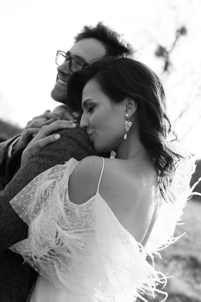 Brautpaar umarmt sich liebevoll in einer romantischen Schwarz-Weiß-Aufnahme.