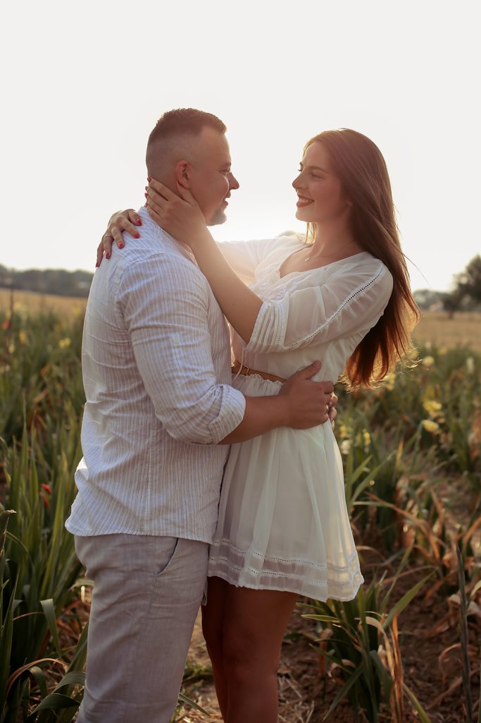 Ein Paar umarmt sich in einem Feld, warmes Licht umgibt sie.