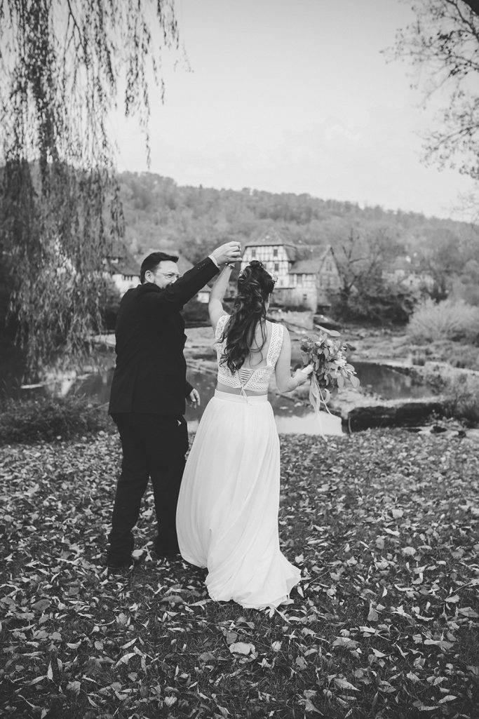 Brautpaar tanzt im Freien, umgeben von herbstlichen Blättern und einer idyllischen Landschaft.