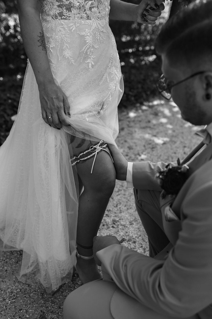 Ein Bräutigam ziert die Beinmitte seiner Braut während einer Hochzeitszeremonie.