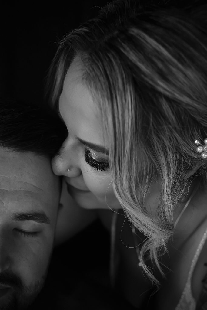 Nahaufnahme eines Brautpaars mit Nähe und Zärtlichkeit, in Schwarz-Weiß. Braut lehnt ihren Kopf an den des Bräutigams.
