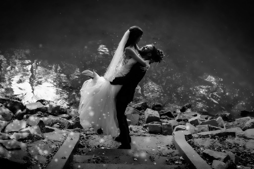 Ein Brautpaar posiert romantisch am Ufer. Der Bräutigam hebt die Braut hoch in die Luft.