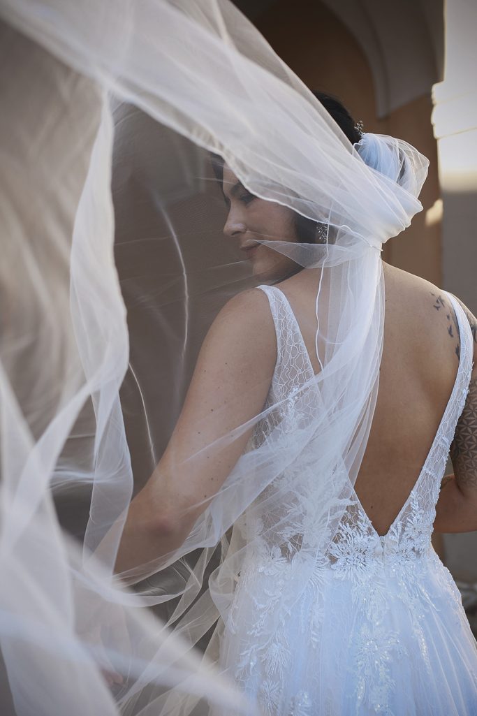 Braut in elegantem Kleid und transparentem Schleier, Blick über die Schulter.