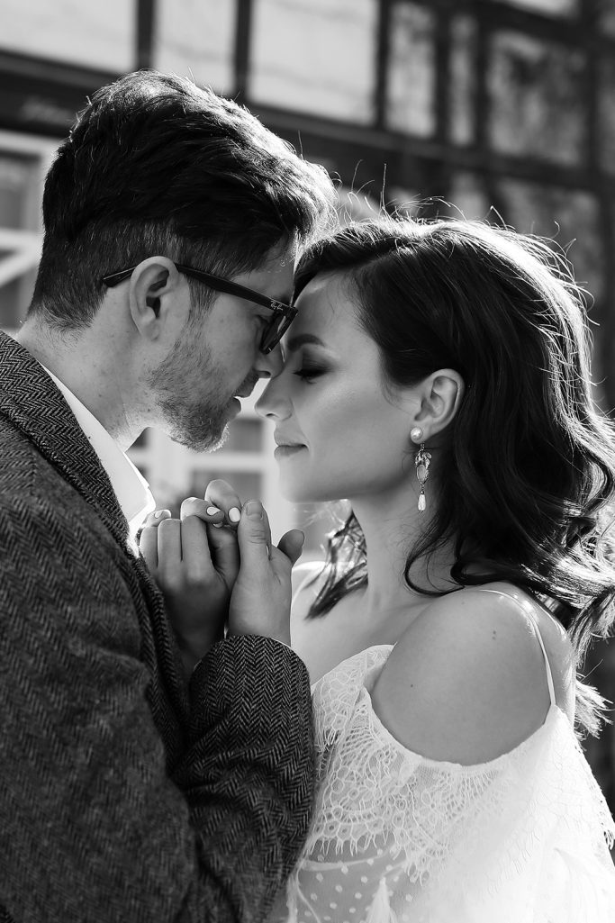 Brautpaar in Zweisamkeit, ihre Stirnen berühren sich, romantische Stimmung, Schwarz-Weiß.