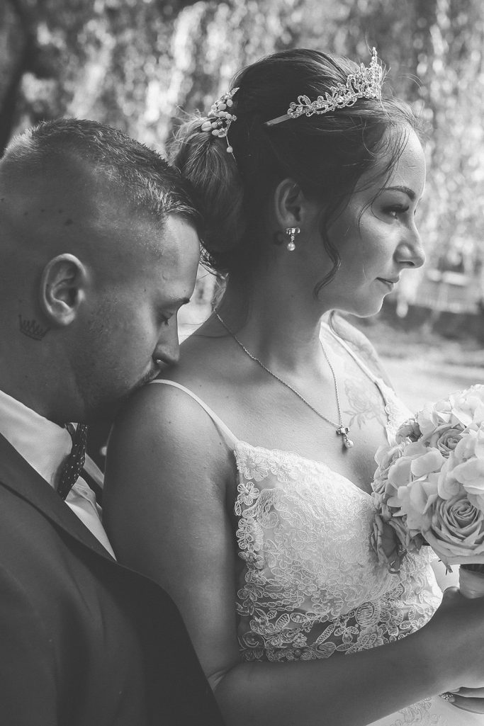 Braut und Bräutigam in einer emotionalen Umarmung, festlich gekleidet. Die Braut hält einen Blumenstrauß in der Hand.