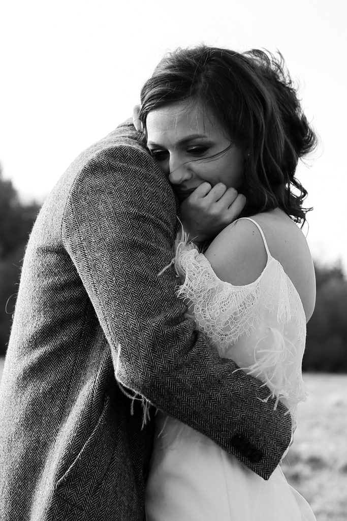 Brautpaar umarmt sich innig, die Braut wirkt emotional in einem romantischen Moment.