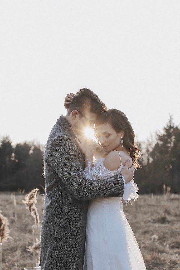 Ein Paar umarmt sich, während die Sonne hinter ihnen untergeht. Romantische Atmosphäre.