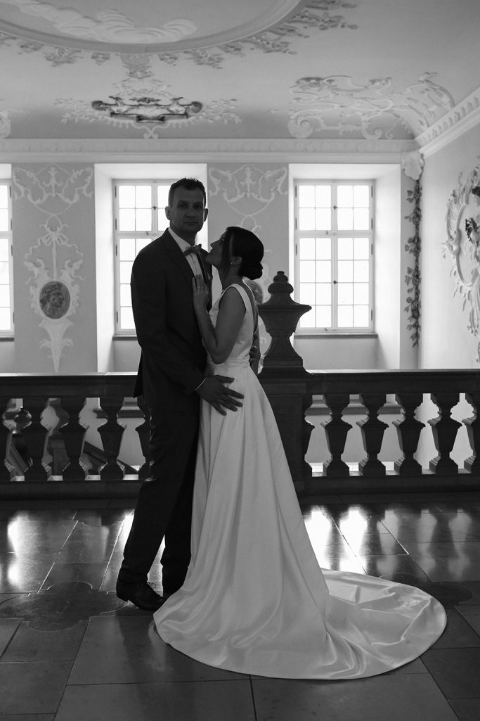 Hochzeitsfoto eines Paares in eleganter Kleidung, umgeben von eleganter Architektur.