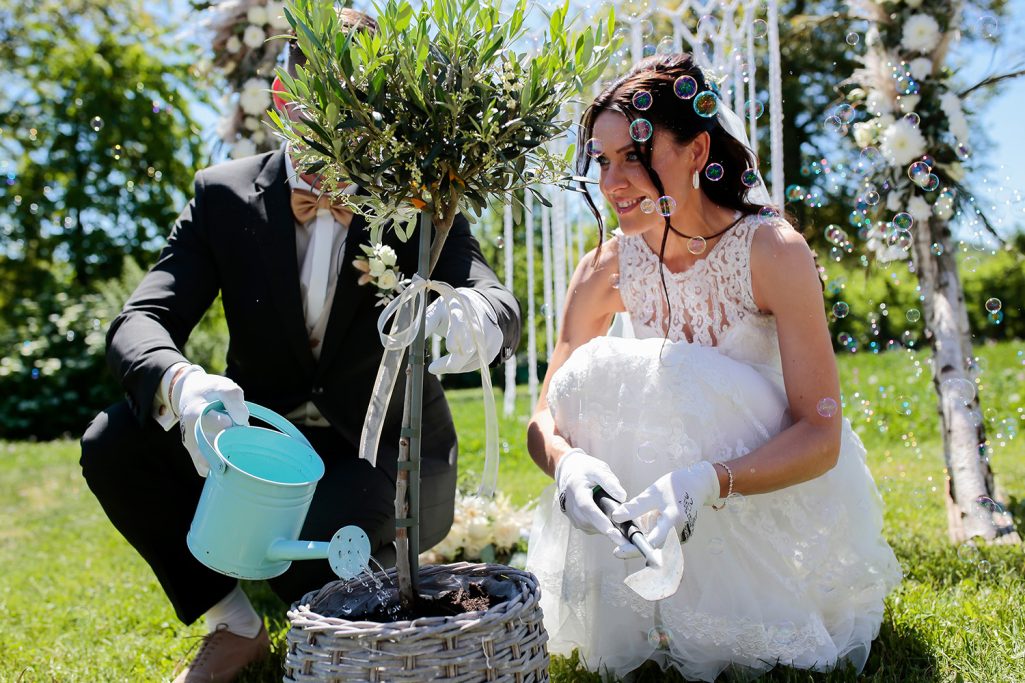 Ein Brautpaar pflanzt einen Baum und gießt ihn, um den Umweltbewusstsein zu symbolisieren.